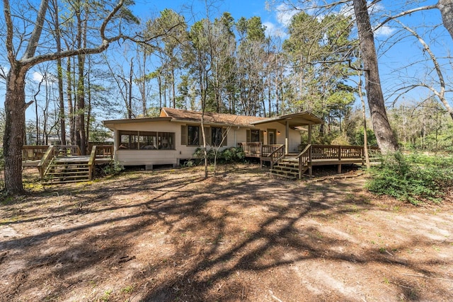 back of property with a sunroom and a deck