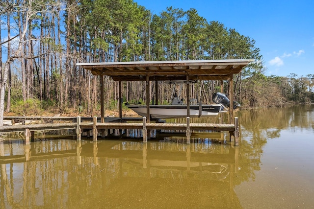 dock area with boat lift, a water view, and a forest view
