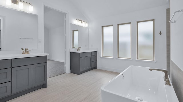 19415 Sorrel Stallion Trl, Tomball, TX 77377 - full bathroom with two vanities, a freestanding tub, lofted ceiling, and wood finished floors