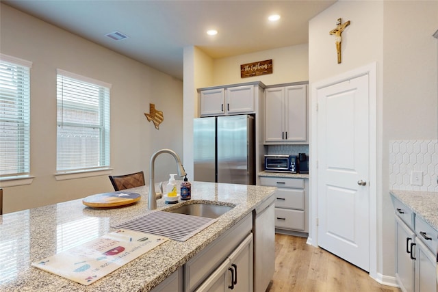 21586 Jordan Pond Rdg, Porter, TX 77365 - kitchen with freestanding refrigerator, a sink, light stone countertops, light wood finished floors, and recessed lighting