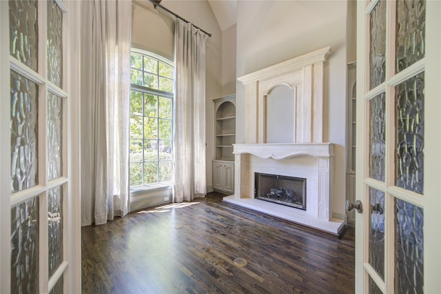 3702 Blue Bonnet, Houston, TX 77025 - unfurnished living room with dark wood-style flooring, a fireplace with raised hearth, a high ceiling, and french doors