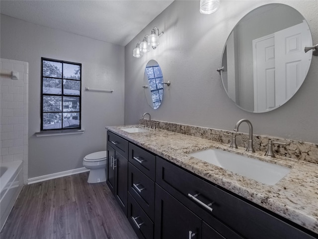 full bathroom with toilet, wood finished floors, a sink, and double vanity