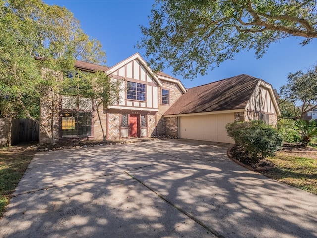 english style home featuring concrete driveway and fence