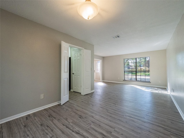 empty room with visible vents, baseboards, and dark wood-type flooring