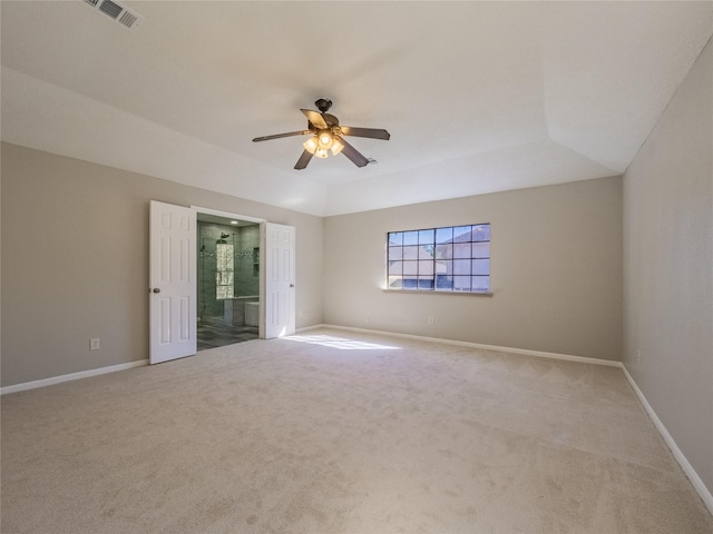 carpeted spare room with baseboards, a ceiling fan, a tray ceiling, and visible vents