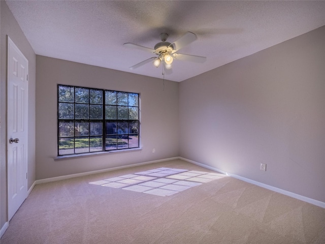 carpeted spare room featuring a textured ceiling, a ceiling fan, and baseboards