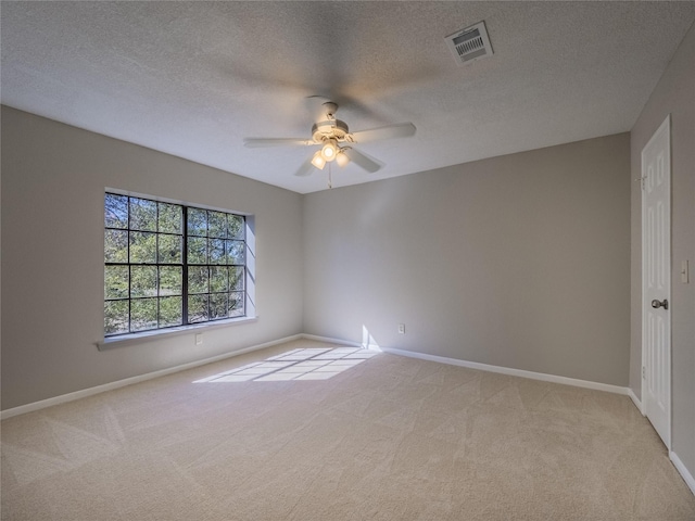 spare room with baseboards, visible vents, light colored carpet, and ceiling fan