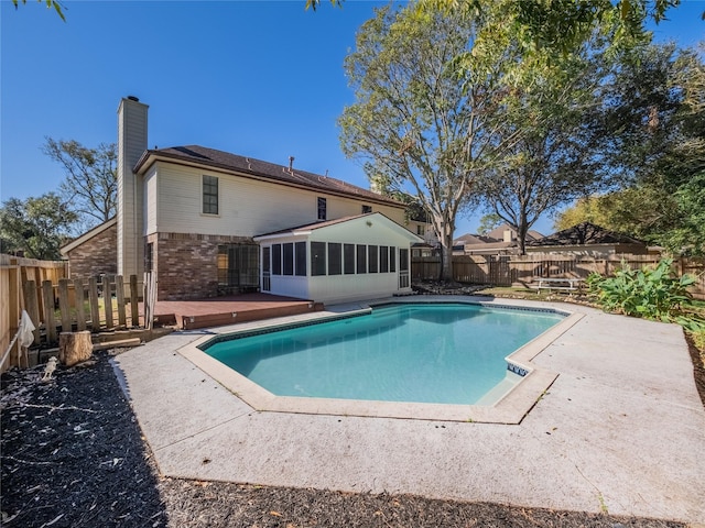 view of pool featuring a fenced in pool, a fenced backyard, a wooden deck, a patio area, and a sunroom