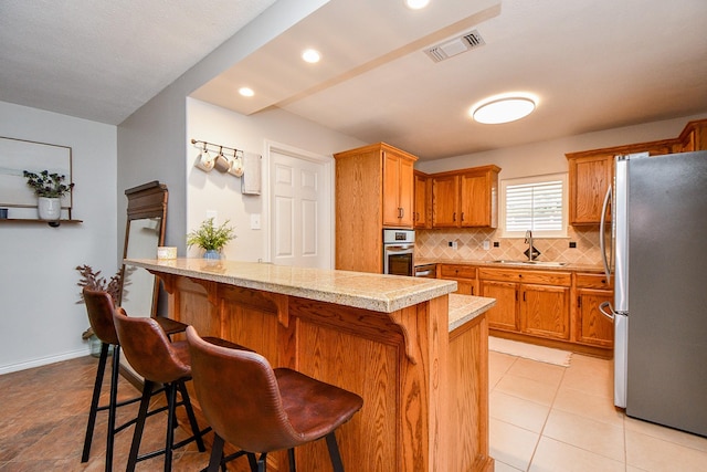 5521 Rosewood Dr, Galveston, TX 77551 - kitchen featuring light countertops, visible vents, appliances with stainless steel finishes, a sink, and backsplash