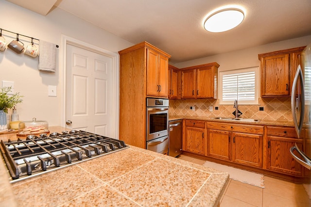 5521 Rosewood Dr, Galveston, TX 77551 - kitchen featuring a sink, brown cabinets, a warming drawer, and appliances with stainless steel finishes