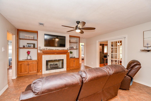 5521 Rosewood Dr, Galveston, TX 77551 - living area featuring baseboards, built in shelves, visible vents, a tile fireplace, and ceiling fan