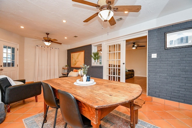 5521 Rosewood Dr, Galveston, TX 77551 - dining room featuring light tile patterned floors, brick wall, ceiling fan, and visible vents