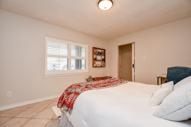 5521 Rosewood Dr, Galveston, TX 77551 - bedroom with light tile patterned floors, baseboards, and a textured ceiling