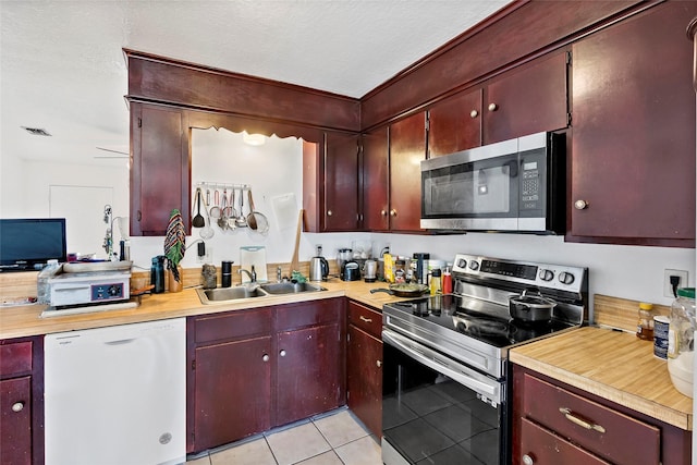 1520 Hillside Dr, College Station, TX 77845 - kitchen with dark brown cabinets, a sink, light tile patterned floors, stainless steel appliances, and light countertops