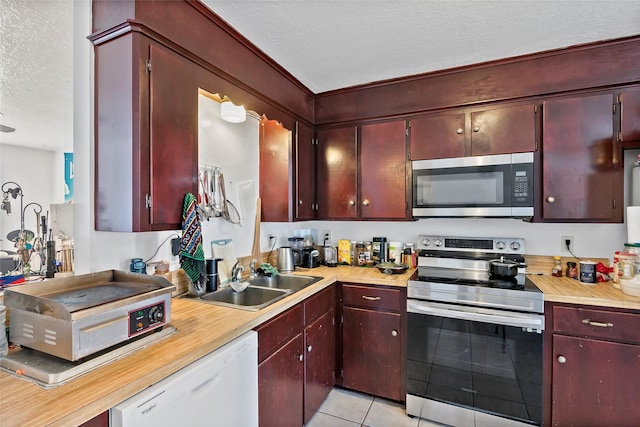 1520 Hillside Dr, College Station, TX 77845 - kitchen with light countertops, reddish brown cabinets, a sink, a textured ceiling, and appliances with stainless steel finishes