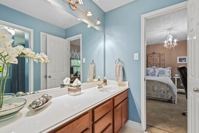 ensuite bathroom with vanity, a chandelier, and baseboards