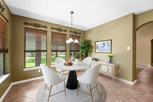dining room featuring light tile patterned floors, a chandelier, baseboards, and arched walkways
