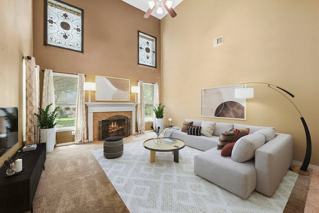 living room featuring a high ceiling, ceiling fan, a premium fireplace, carpet floors, and baseboards