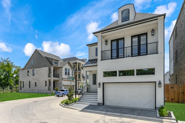view of front of property with a standing seam roof, fence, an attached garage, a balcony, and metal roof