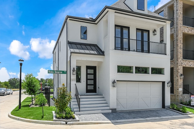 view of front of home featuring stucco siding, a standing seam roof, metal roof, an attached garage, and driveway