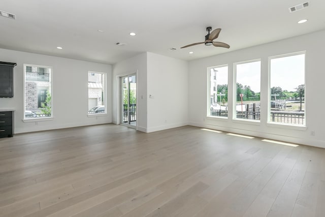unfurnished living room featuring light wood-type flooring, a wealth of natural light, and visible vents