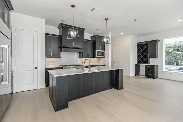 kitchen with visible vents, stainless steel microwave, tasteful backsplash, and light wood finished floors