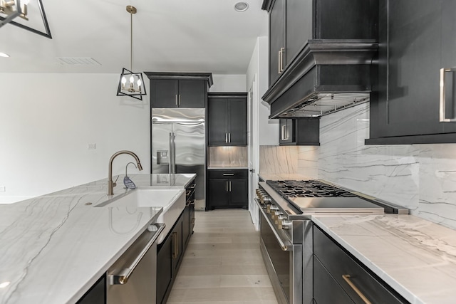 kitchen with visible vents, light stone countertops, a sink, premium appliances, and backsplash