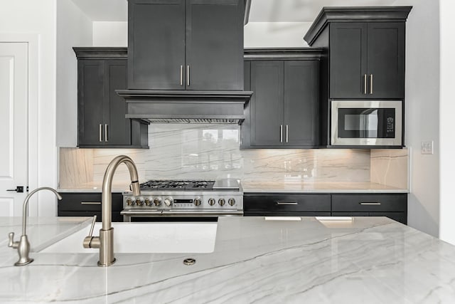 kitchen with light stone countertops, stainless steel appliances, tasteful backsplash, and exhaust hood