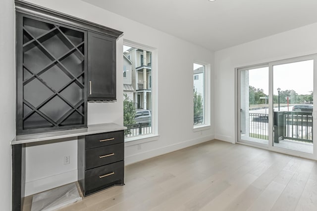 unfurnished office with baseboards and light wood-type flooring