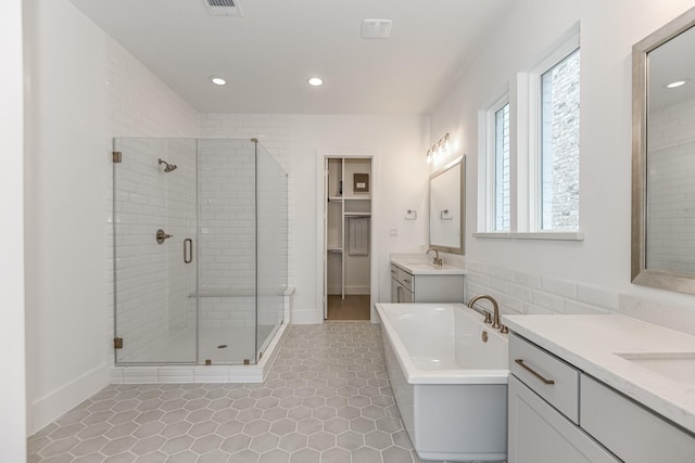 full bathroom with a stall shower, a sink, two vanities, a soaking tub, and recessed lighting