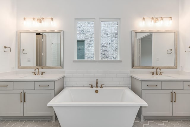 bathroom with a freestanding bath, a sink, and two vanities