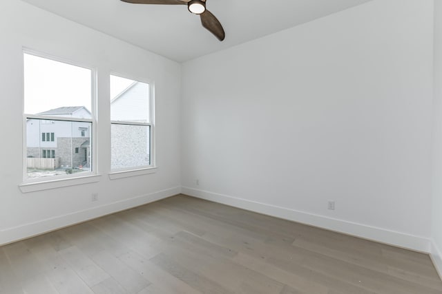 spare room with light wood-type flooring, baseboards, and ceiling fan