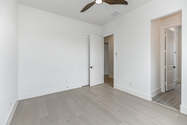unfurnished bedroom with baseboards, light wood-style flooring, visible vents, and a ceiling fan