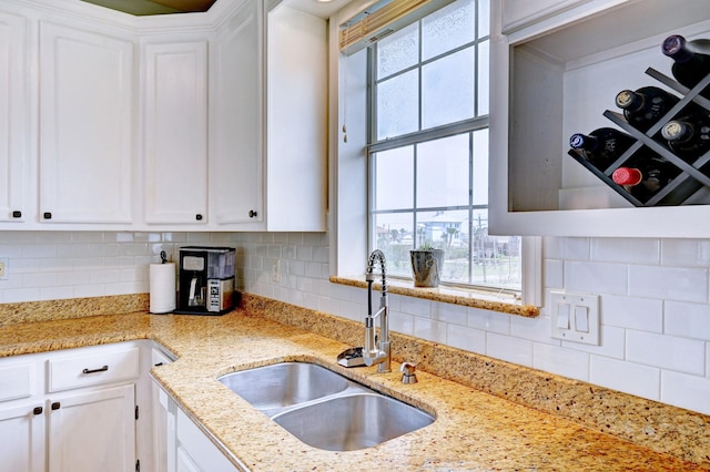 9605 Teichman Rd, Galveston, TX 77554 - kitchen featuring a sink, tasteful backsplash, white cabinetry, and light stone countertops
