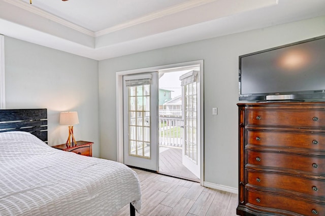 9605 Teichman Rd, Galveston, TX 77554 - bedroom with baseboards, light wood-type flooring, crown molding, a tray ceiling, and access to exterior