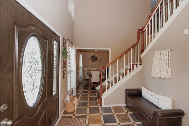 foyer featuring stairs, baseboards, and a towering ceiling