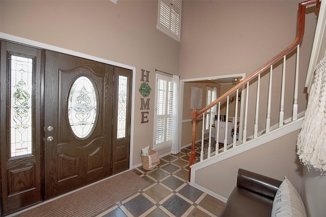 foyer featuring stairway, baseboards, and a towering ceiling