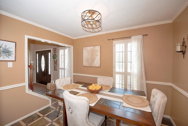 dining room with inlaid floor details, crown molding, baseboards, and a chandelier