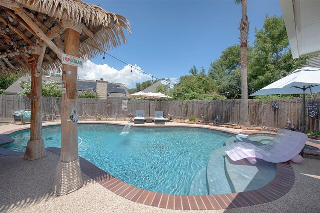 view of pool featuring a fenced backyard and a pool with connected hot tub