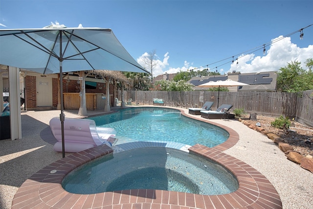 view of swimming pool featuring a fenced backyard, a pool with connected hot tub, and a patio area