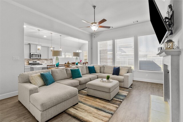 4831 Dove Cove Ln, League City, TX 77573 - living area with crown molding, baseboards, light wood-style floors, visible vents, and ceiling fan