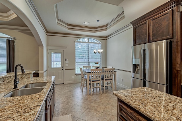 kitchen featuring stainless steel fridge with ice dispenser, a raised ceiling, a sink, arched walkways, and dark brown cabinetry