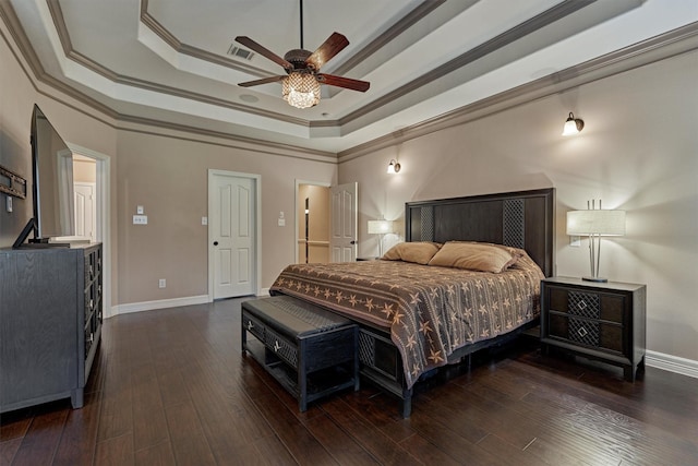 bedroom featuring a tray ceiling, hardwood / wood-style floors, ornamental molding, baseboards, and visible vents