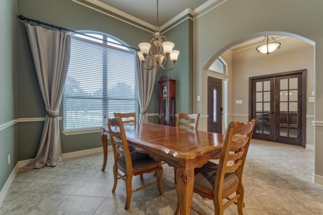 dining area featuring french doors, a chandelier, baseboards, arched walkways, and ornamental molding