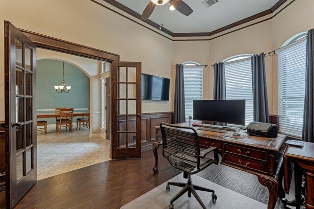 home office featuring a wainscoted wall, crown molding, french doors, ceiling fan with notable chandelier, and dark wood-style flooring
