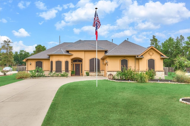 view of front of property featuring a front yard, stucco siding, stone siding, and curved driveway