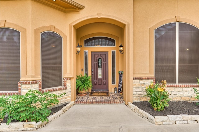 view of exterior entry featuring stone siding and stucco siding