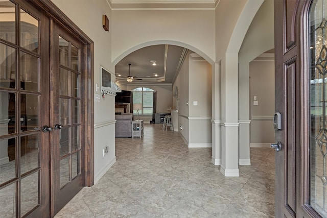 entryway featuring crown molding, french doors, baseboards, arched walkways, and ceiling fan