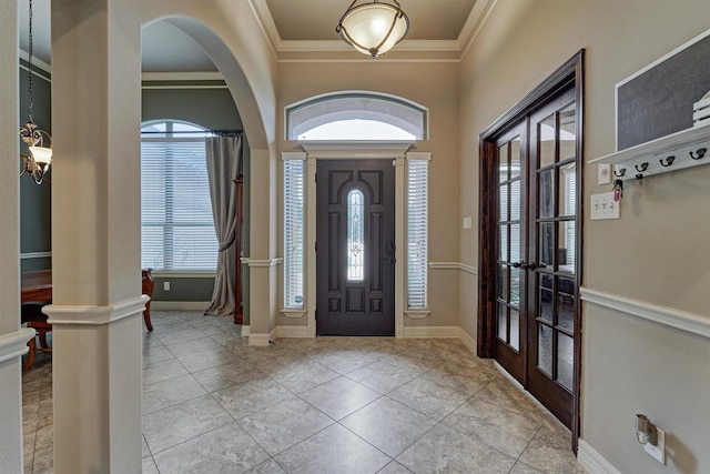 tiled entrance foyer featuring baseboards, crown molding, arched walkways, and french doors