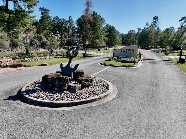 view of road featuring a gated entry, a gate, and curbs